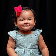Cami joined the competition — help win amazing prizes! adorable, baby, black_background, blue_outfit, bow, child, chubby_cheeks, clothing, cute, happy, infant, ladybug_pattern, person, pink_bow, portrait, short_hair, sitting, smile, studio_photo, young_child