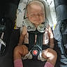 baby, car_seat, infant, sleeping, pink_socks, mittens, straps, child, face, head_support, safety_harness, clothing, cute, resting, indoors, comfort, seat, portrait, peaceful, newborn