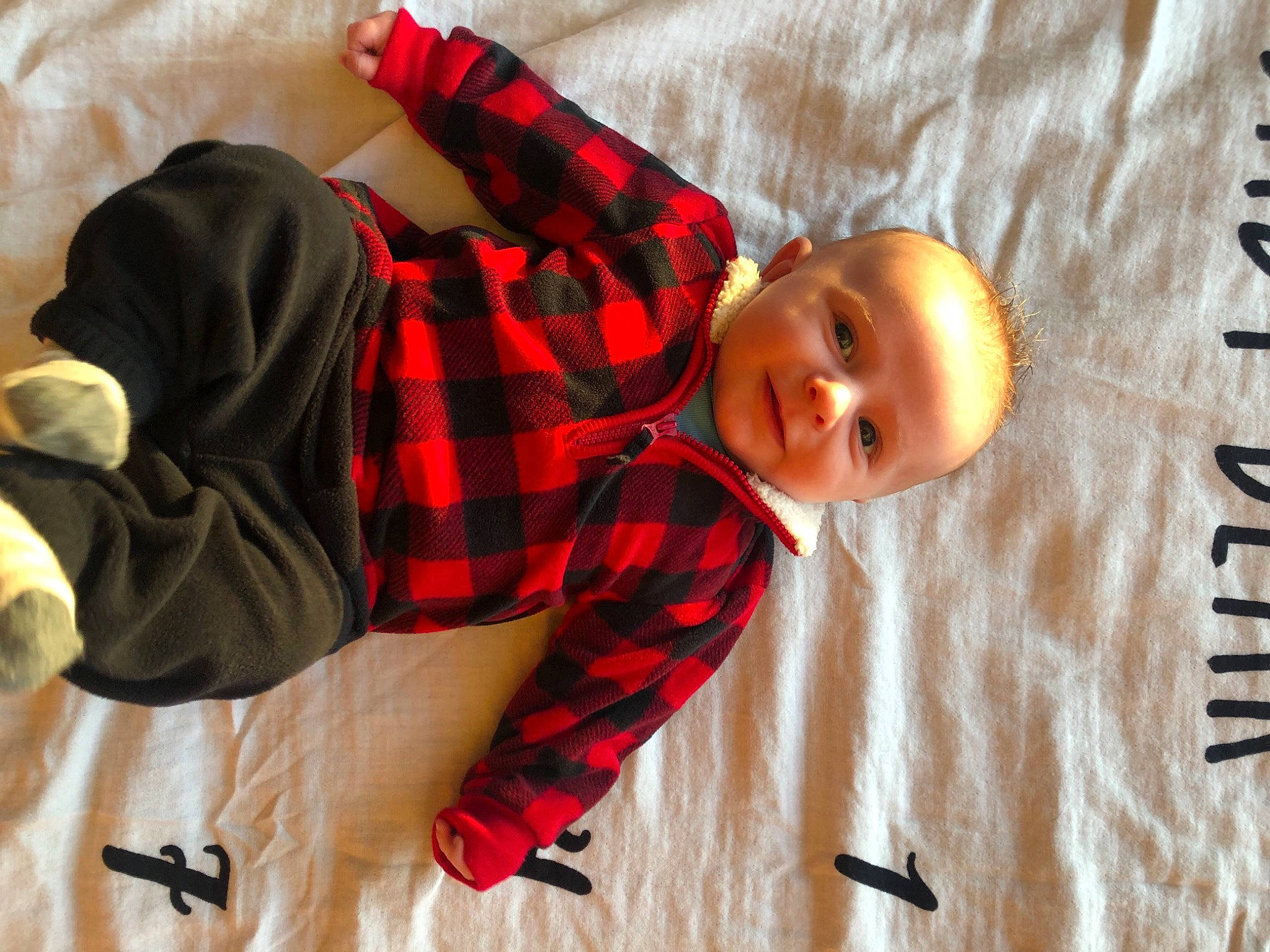 Braxton is registered to the contest to win money with this photo: arm, baby, child, comfort, face, flooring, fun, happy, head, mammal, orange, pattern, people, person, plaid, sleeve, smile, tartan, textile, toddler