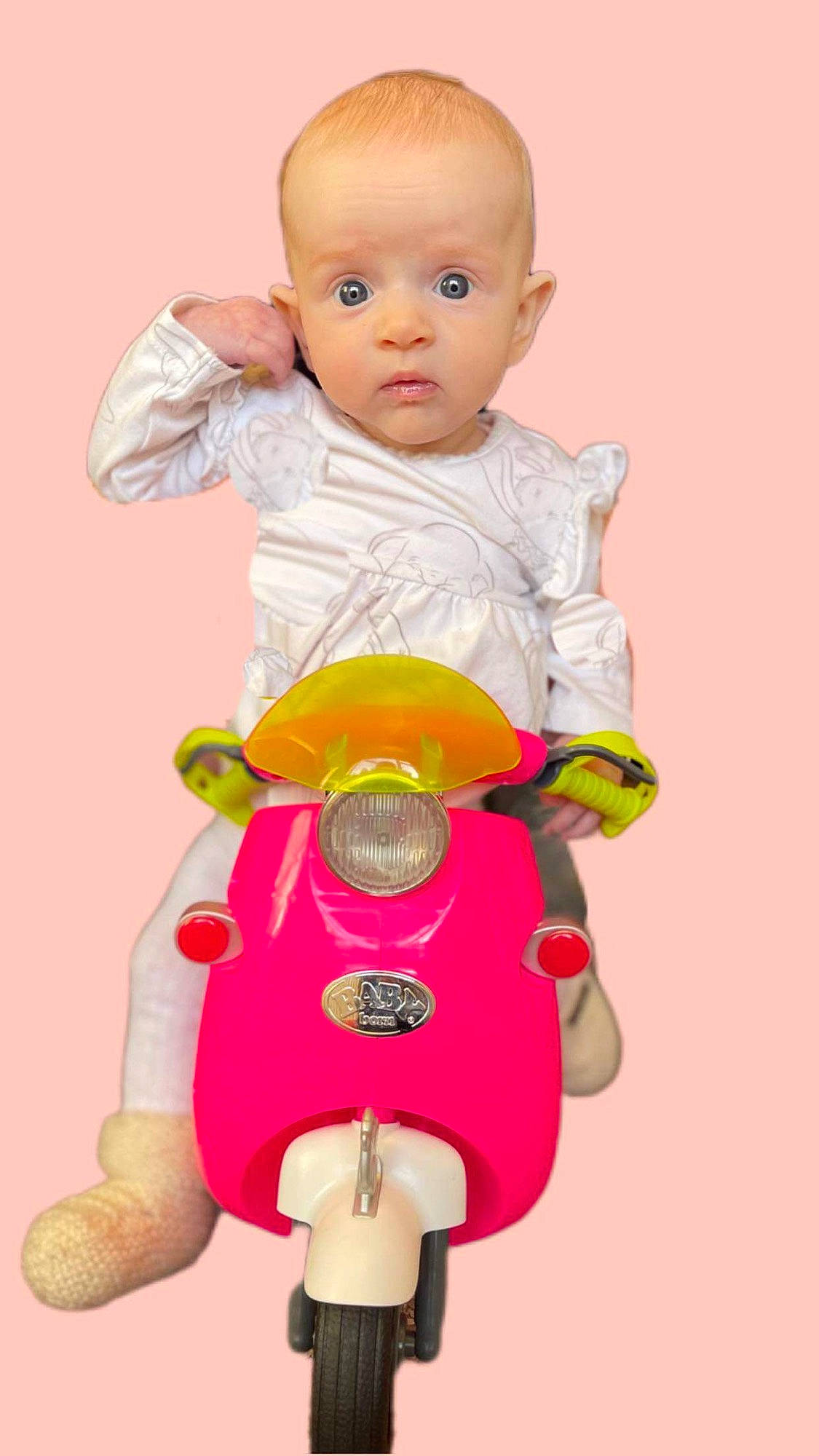 Dottie is registered to the contest to win money with this photo: arm, baby, baby_products, baby_toddler_clothing, cheek, child, gesture, hand, happy, head, human_body, magenta, person, pink, product, riding_toy, skin, sleeve, surprise, toddler