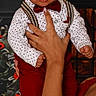 baby, child, infant, red_bow_tie, suspenders, white_shirt, polka_dots, hand, adult, portrait, indoor, fashion, cute, person, holding, smiling, face, background, clothing, happy