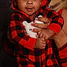 baby, child, red_pajamas, hoodie, plush_toy, hand, person, indoor, window, pattern, matching_outfits, smile, cute, cozy, holding, socks, adult, face, portrait, warm_lighting