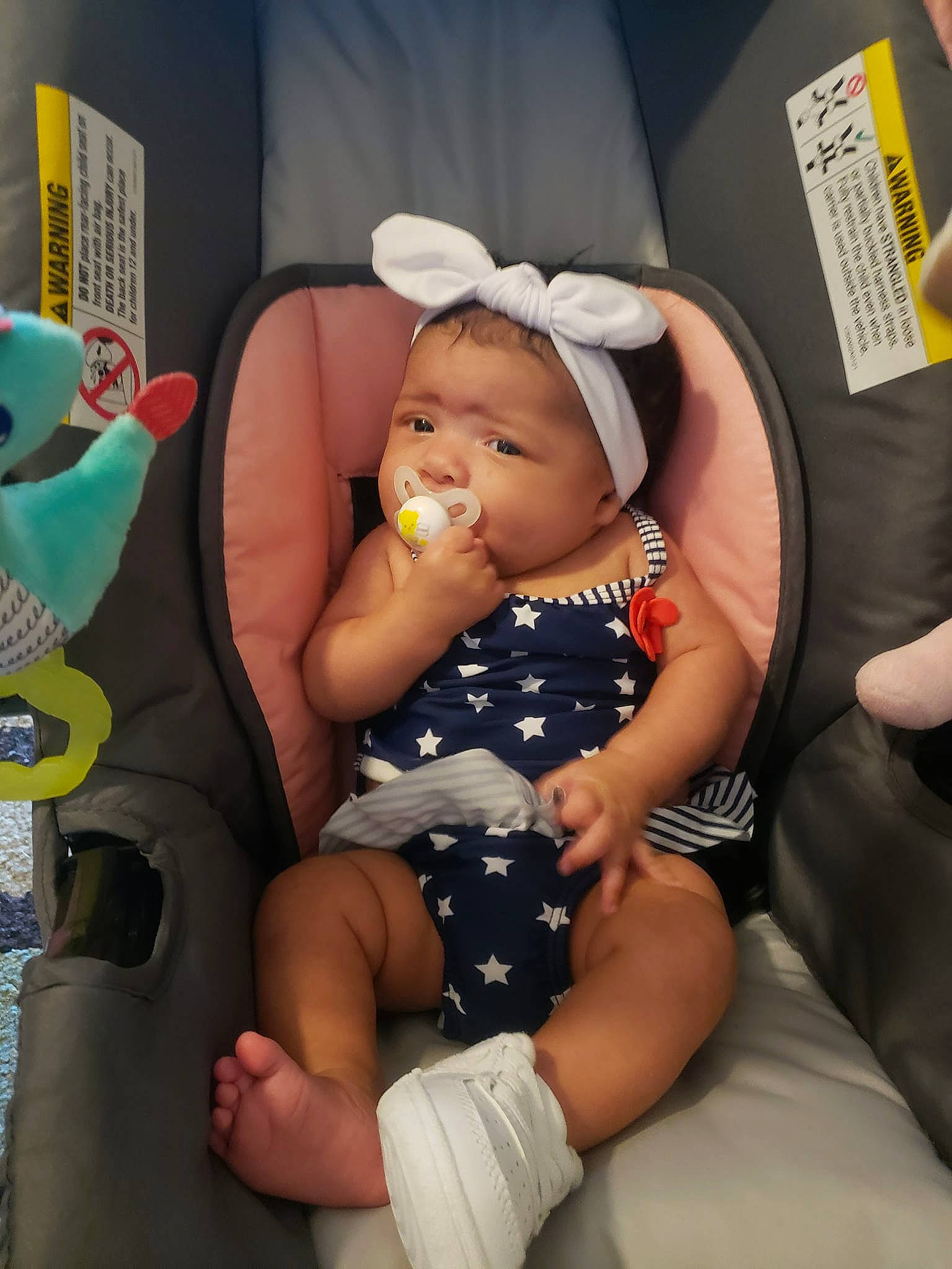 Annalise is registered to the contest to win money with this photo: arm, baby, baby_toddler_clothing, car_seat, chair, cheek, child, comfort, finger, hairstyle, hat, human_body, knee, lap, leg, person, pink, product, skin, thigh