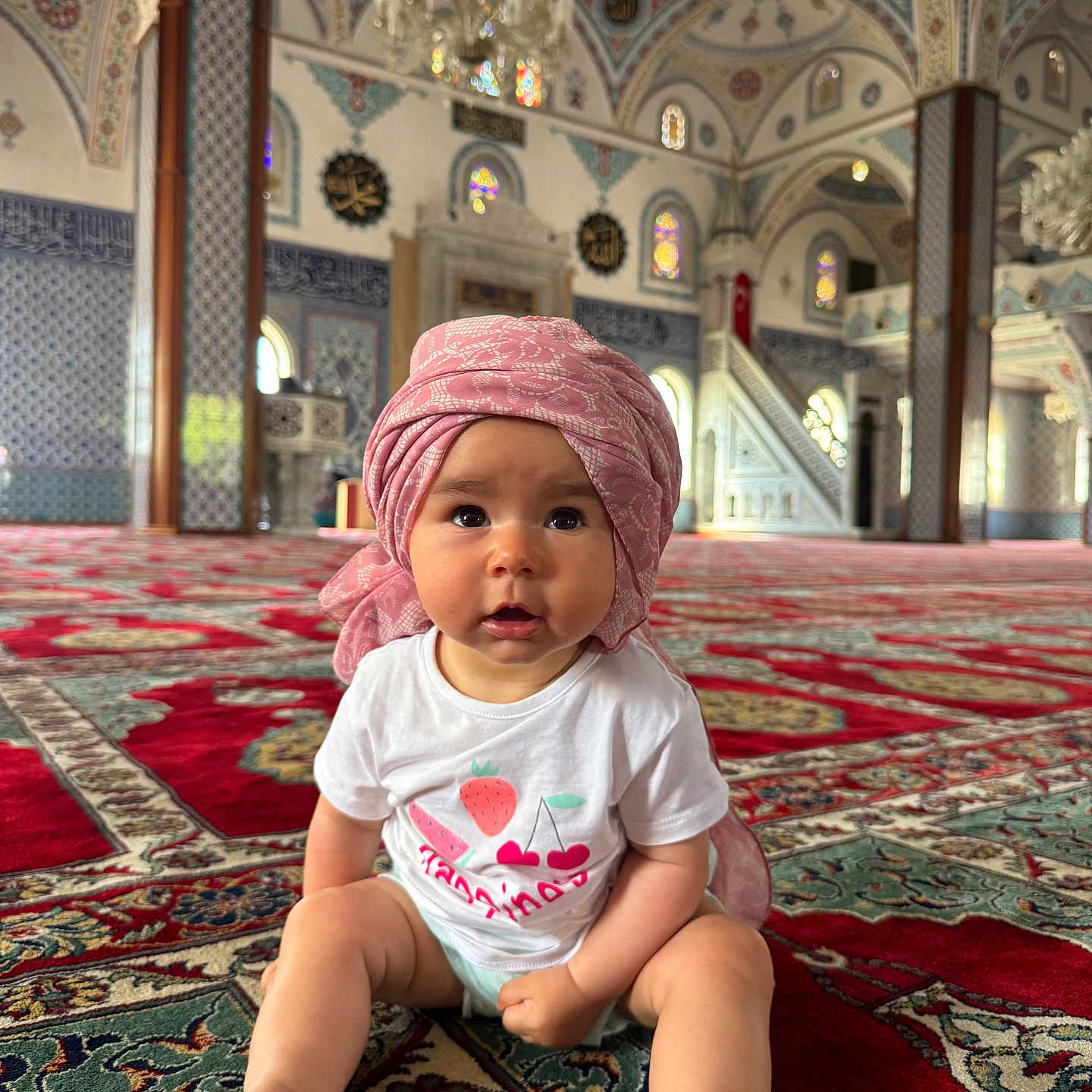 Aelis a rejoint le concours — aidez-le/la à gagner de superbes lots ! architecture, baby, carpet, child, colorful, curious, decorative, fruit_graphics, headwear, indoor, mosque, patterned_floor, person, portrait, religious_building, sitting, soft_lighting, stained_glass, turban, white_shirt