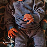 Kamari is registered to the contest to win money with this photo: baby, infant, pajamas, blanket, pattern, face, hand, lying_down, indoors, cute, child, smiling, skin, head, person, portrait, cozy, warm_lighting, digital_overlay, text_overlay