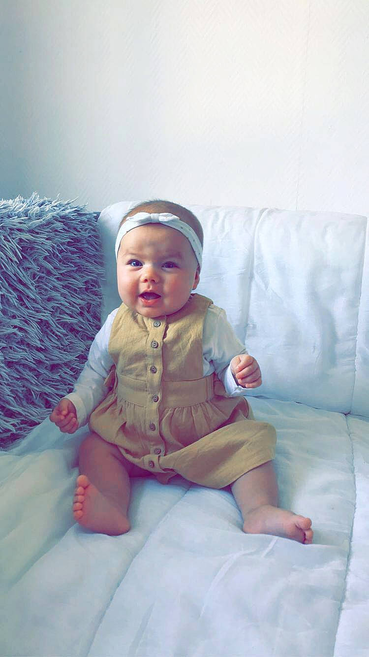 Leya a rejoint le concours — aidez-le/la à gagner de superbes lots ! baby, baby_toddler_clothing, comfort, couch, dress, flash_photography, foot, fun, happy, headwear, human_leg, iris, knee, leg, linens, person, sitting, skin, sleeve, smile