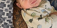 Charles participe au concours pour gagner de l'argent avec cette photo : baby, child, infant, tattoo, arm, cushion, patterned, dinosaur_print, sweater, smile, face, eyes, cozy, indoor, person, holding, comfort, cute, expression, closeup
