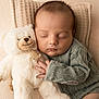baby, sleeping, teddy_bear, plush_toy, knitted_sweater, cozy, cuddle, soft_toy, infant, child, cute, peaceful, portrait, close_up, indoors, warm_colors, blanket, relaxation, comfort, furniture