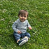Hayden a rejoint le concours — aidez-le/la à gagner de superbes lots ! baby, casual_clothing, child, cute, daylight, flowers, grass, greenery, nature, outdoor, pants, person, playful, portrait, shoes, sitting, smile, striped_shirt, toddler, young_child