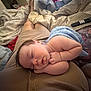 baby, bed, blanket, blue_blanket, child, comfort, cozy, face, furniture, hand, indoor, lap, napping, peaceful, person, remote_control, resting, skin, sleeping, soft