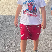 Lucciano participe au concours pour gagner de l'argent avec cette photo : child, curly_hair, walking, street, tshirt, shorts, spiderman, sandals, sidewalk, car, outdoor, sunlight, casual_clothing, red, white, person, summer, young, kid, fashion