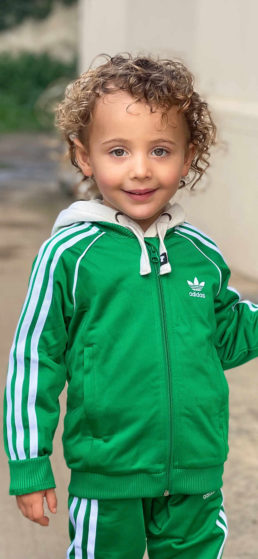 Lucciano a rejoint le concours — aidez-le/la à gagner de superbes lots ! child, curly_hair, green_tracksuit, adidas, smiling, outdoor, hoodie, jacket, pants, person, young_child, happy, casual_wear, portrait, fashion, street, cute, kid, standing, apparel