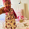 Janelis joined the competition — help win amazing prizes! baby, child, girl, headband, pink, floral_dress, smiling, tongue_out, bed, blanket, stuffed_animal, toy, hand_holding, milestone, eleven_months, cute, indoors, happy, person, portrait