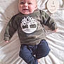 baby, infant, smiling, camo_sweater, navy_pants, blanket, wooden_sign, balloon_shape, four_months, lying_down, cute, happy, indoors, soft_texture, child, person, clothing, face, hand, foot