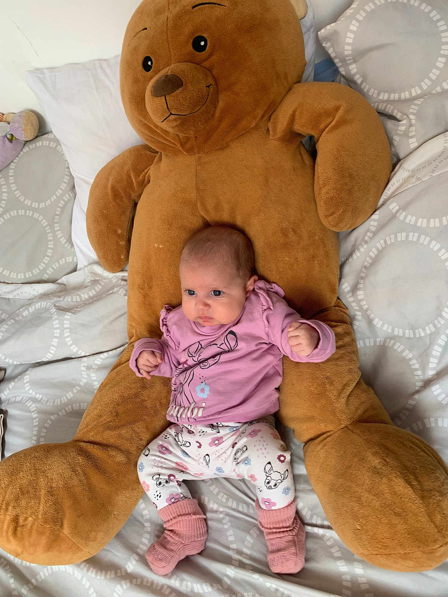 Mia a rejoint le concours — aidez-le/la à gagner de superbes lots ! baby, infant, plush_toy, teddy_bear, bed, pillow, blanket, pink_clothing, patterned_pants, socks, person, child, indoor, cute, soft_toy, sleepwear, resting, small_hands, face, lying_down