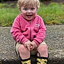 toddler, child, smiling, outdoor, grass, puddle, rain_boots, yellow_boots, pink_jacket, shorts, blonde_hair, happy, sitting, curb, nature, greenery, boots, playful, water, casual_clothing