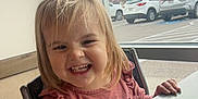 Josie is registered to the contest to win money with this photo: car, casual, chair, child, clothing, daylight, face, hair, hand, happy, indoor, long_sleeve, parking_lot, person, pink, smile, table, toddler, window, wood