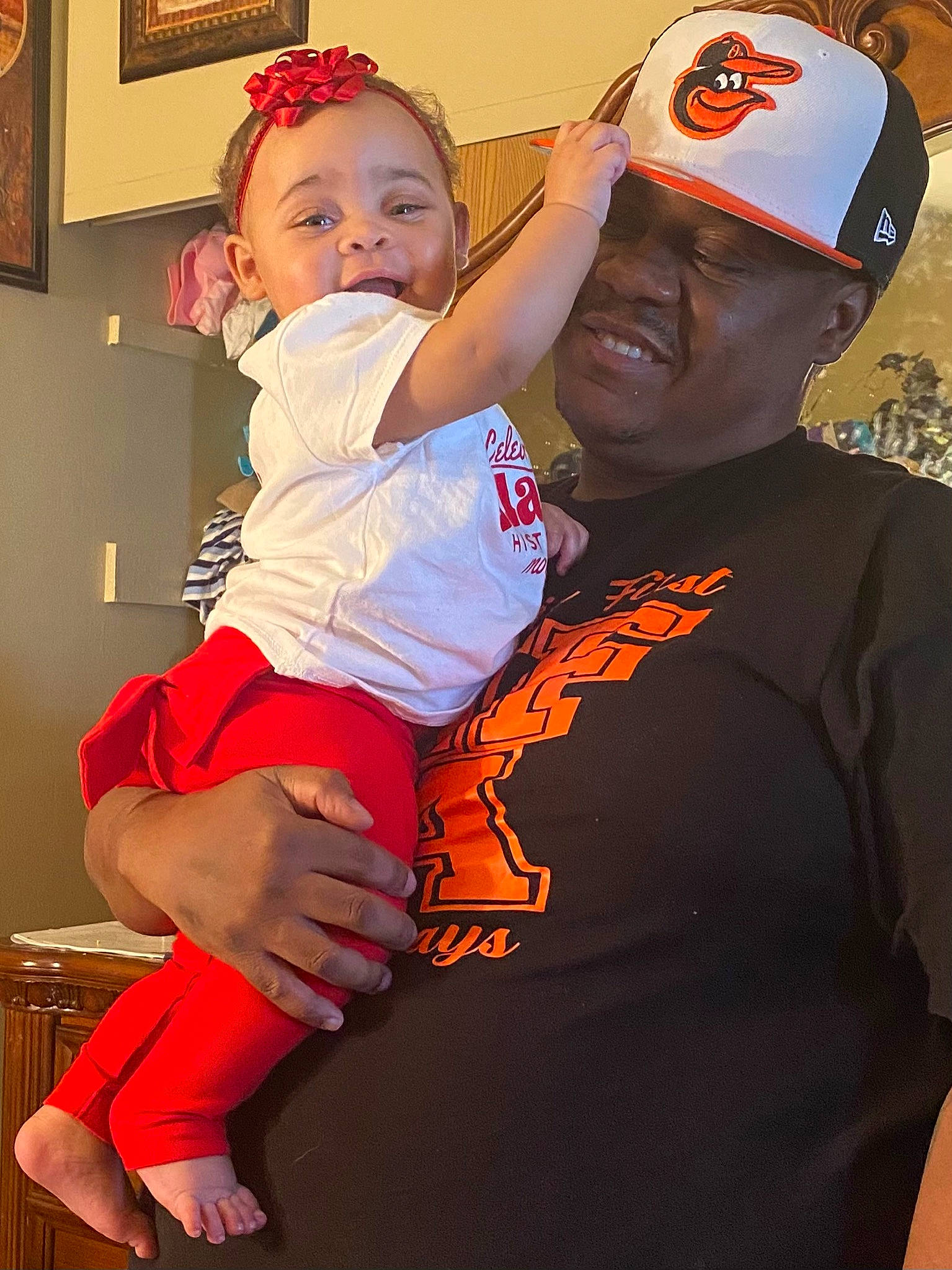 Jada joined the competition — help win amazing prizes! baby, baseball_cap, cap, child, event, fun, gesture, happy, hat, headgear, headwear, hug, person, personal_protective_equipment, picture_frame, recreation, red, smile, t_shirt, thigh