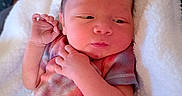 Jaxon is registered to the contest to win money with this photo: baby, newborn, infant, blanket, clothing, colorful, tie_dye, soft, cute, sleeping, hands, face, skin, portrait, indoors, child, person, resting, cozy, cute_expression