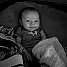 Jaxon is registered to the contest to win money with this photo: baby, infant, blanket, striped_clothing, smile, face, hand, portrait, black_and_white, cozy, cute, child, lying_down, fabric, soft_texture, young, person, indoors, expression, resting