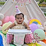 baby, birthday, half_birthday, high_chair, party_hat, balloons, plush_toys, tent, outdoor, grass, fence, smiling, celebration, colorful, decorations, child, cute, festive, happy, portrait