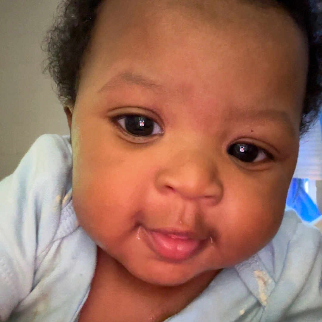 Obsidian is registered to the contest to win money with this photo: baby, infant, face, child, cute, smile, eyes, hand, curly_hair, clothing, indoor, portrait, skin, young_child, person, closeup, expression, baby_garment, human, toddler