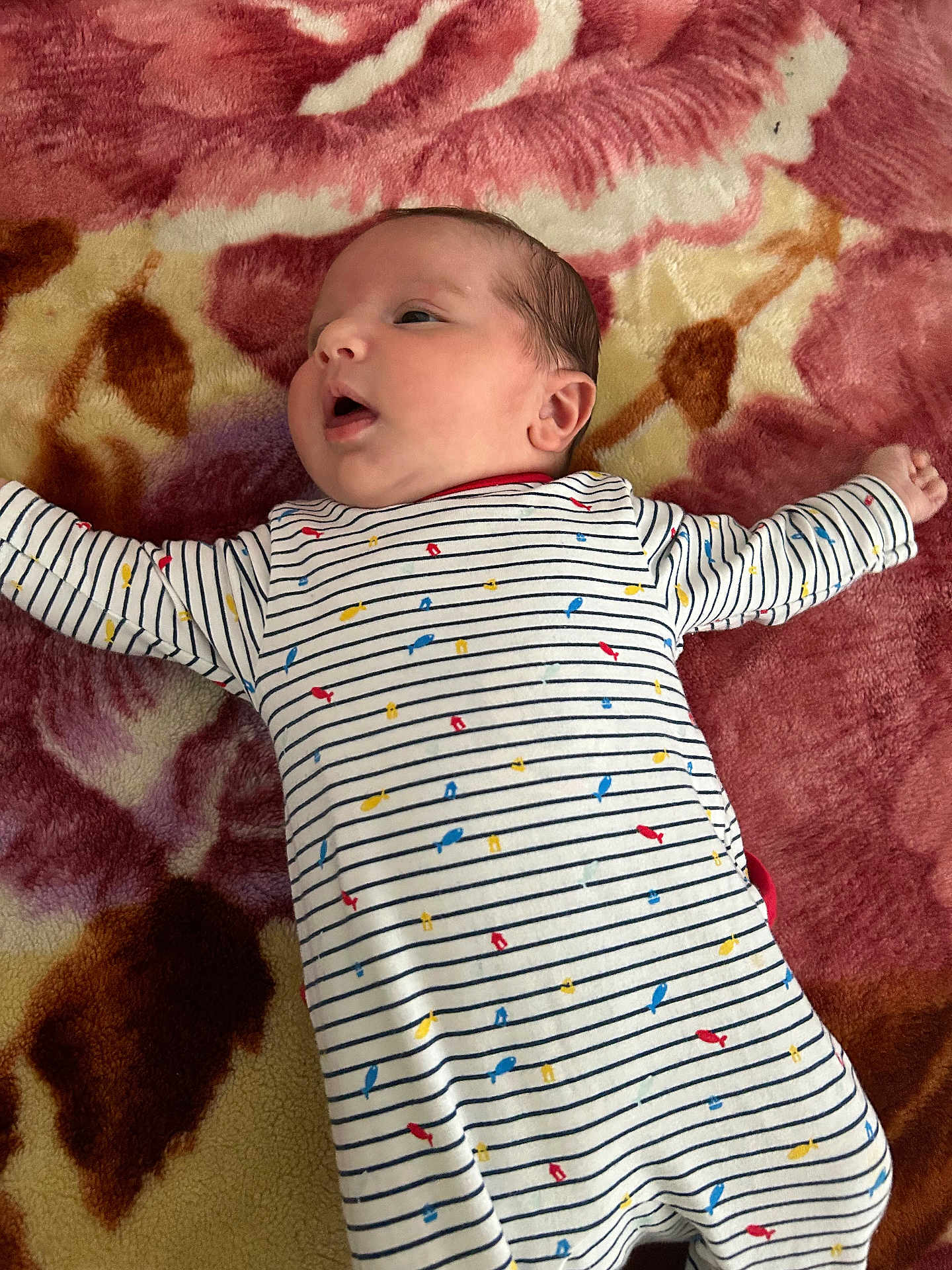 Qassim participe au concours pour gagner de l'argent avec cette photo : baby, infant, child, blanket, pattern, striped_clothing, onesie, colorful, fish_print, lying_down, curious, face, head, arm, skin, indoors, soft_texture, young_child, cute, sleepwear