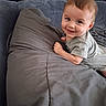 baby, bed, child, clothing, cute, eyes, face, gray, hair, hand, happy, headboard, indoors, infant, person, pillow, portrait, skin, smiling, toddler