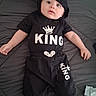 Ian is registered to the contest to win money with this photo: baby, black_clothing, child, cute, expression, eyes, face, foot, hand, hood, indoor, infant, king_text, lying_down, onesie, person, portrait, quilted_bedspread, shorts, young_child