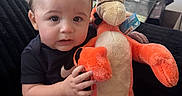 Ian joined the competition — help win amazing prizes! baby, black_clothing, child, couch, curious, cute, expression, hand, home, indoor, natural_light, person, plush_toy, short_hair, sitting, soft_toy, stuffed_animal, tiger, window, young_child