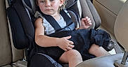 Stevie is registered to the contest to win money with this photo: child, toddler, dog, car, car_seat, seatbelt, passenger, vehicle, indoors, sitting, blonde_hair, serious_expression, pet, black_dog, cuddling, travel, leather_seats, window, portrait, family