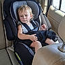 child, toddler, dog, car, car_seat, seatbelt, passenger, vehicle, indoors, sitting, blonde_hair, serious_expression, pet, black_dog, cuddling, travel, leather_seats, window, portrait, family