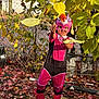 child, costume, mask, pink_boots, autumn_leaves, fall, outdoor, playful, nature, tree, leaves, fence, garden, person, pose, colorful, seasonal, young_child, smiling, fun