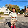 Laura joined the competition — help win amazing prizes! child, outdoor, sunny, blue_sky, rain_boots, pink_boots, curly_hair, white_shirt, cropped_shirt, pants, standing, smiling, sidewalk, residential_area, trees, car, shadow, fence, house, person