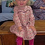 child, toddler, smiling, pink_dress, tights, black_shoes, wooden_furniture, woman, glasses, living_room, couch, blanket, hair_bows, indoor, portrait, happy, person, seated, casual_clothing, family