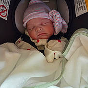 Ariel is registered to the contest to win money with this photo: baby, newborn, infant, sleeping, car_seat, striped_hat, blanket, mittens, cherry_print, harness, seat_padding, portrait, closeup, soft_light, indoors, safety_label, peaceful, wrapped, hat_knot, pink_cheeks