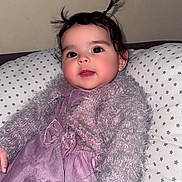 Meïssa a rejoint le concours — aidez-le/la à gagner de superbes lots ! baby, child, pigtails, purple_dress, fluffy_sweater, star_pattern, pillow, indoor, portrait, cute, smiling, young_child, person, face, hair, cozy, relaxed, infant, seated, fashion