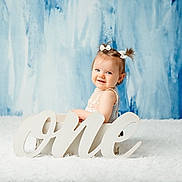 Marie participe au concours pour gagner de l'argent avec cette photo : baby, blue_background, child, cute, face, first_birthday, fluffy_carpet, girl, hair_bows, happy, indoor, infant, one_sign, person, pigtails, portrait, sitting, smiling, studio_photo, white_box