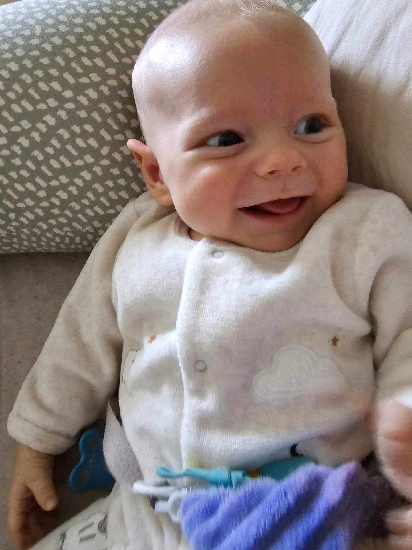 Oscar a rejoint le concours — aidez-le/la à gagner de superbes lots ! baby, infant, smile, joy, pajamas, soft_toy, cushion, pattern, hand, face, child, cozy, cute, lying_down, indoors, happy, closeup, skin, expression, warm