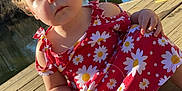 Laiklyn joined the competition — help win amazing prizes! toddler, child, dress, red_clothing, daisy_pattern, barefoot, wooden_dock, river, bridge, outdoor, sunlight, nature, water, reflection, trees, curly_hair, face, portrait, sitting, daytime
