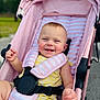 baby, stroller, pink, yellow_outfit, smiling, child, outdoor, happy, cheeks, face, seatbelt, sunlight, portrait, infant, candid, daylight, cute, baby_clothes, safety_harness, person