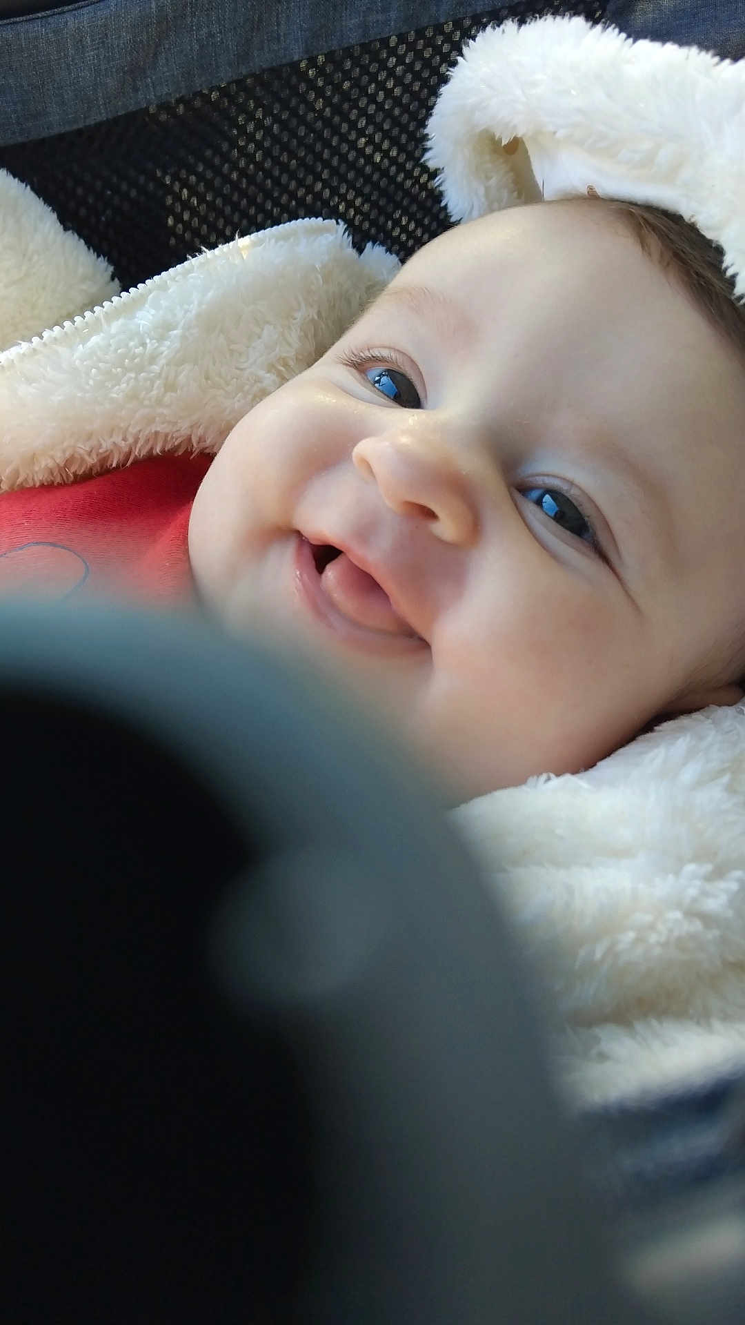 Naïa a rejoint le concours — aidez-le/la à gagner de superbes lots ! baby, infant, smiling, close_up, portrait, blanket, fluffy, car_seat, seat, cheeks, eyes, mouth, tongue, skin, hood, cozy, happy, soft_texture, human, cute