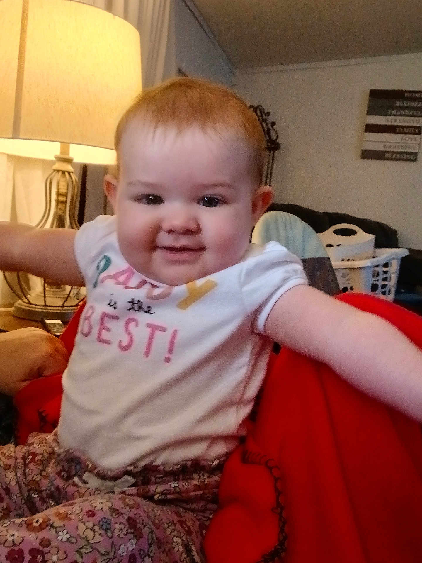 Natalie joined the competition — help win amazing prizes! baby, child, smiling, happy, toddler, clothing, shirt, pants, floral, indoors, lamp, furniture, blanket, red, person, face, home, cozy, expression, sitting