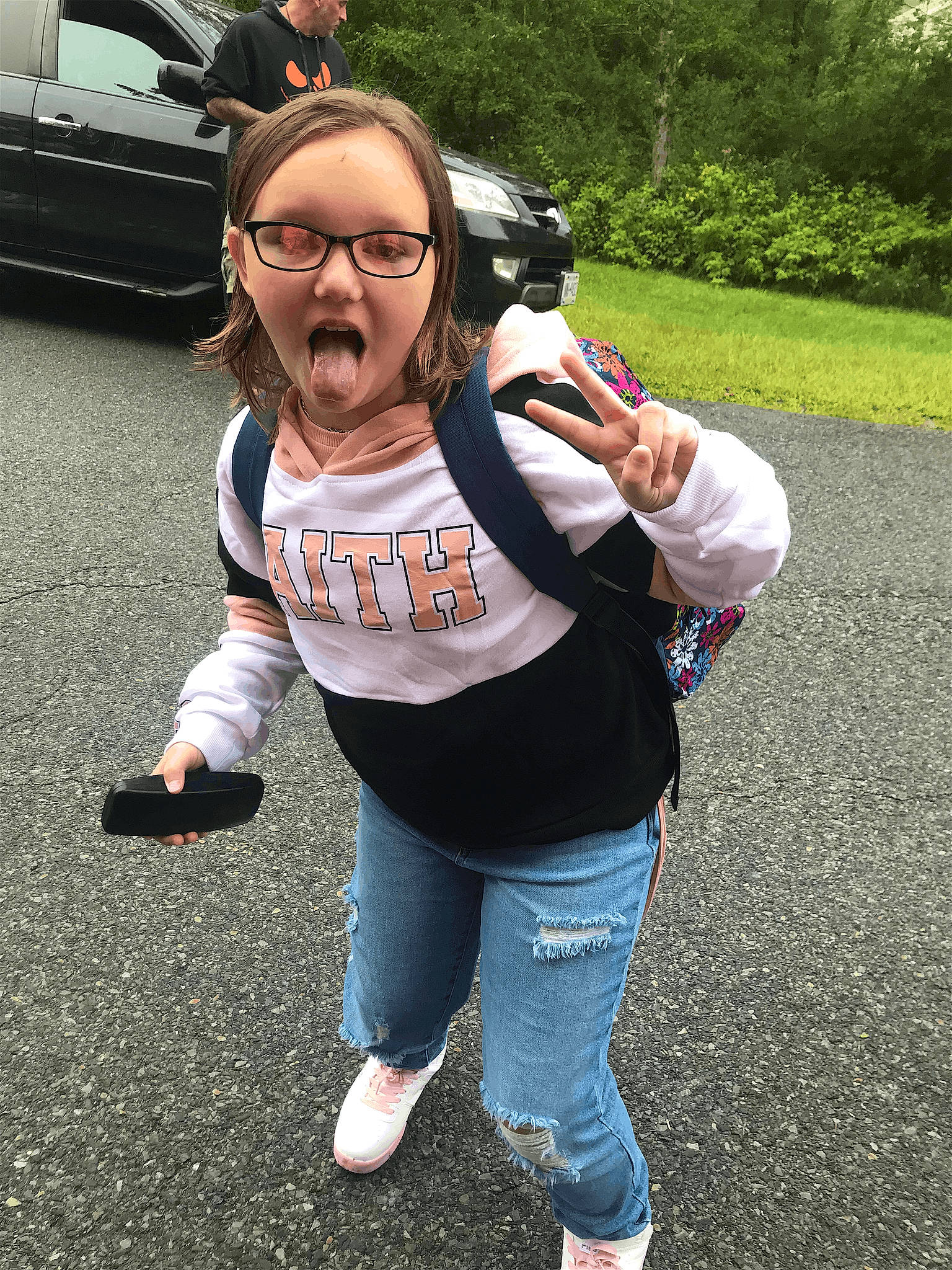 Dakota is registered to the contest to win money with this photo: asphalt, eyewear, family_car, fun, gesture, glasses, goggles, grass, happy, leisure, pedestrian, person, personal_protective_equipment, plant, recreation, road, sneakers, sportswear, sunglasses, vision_care