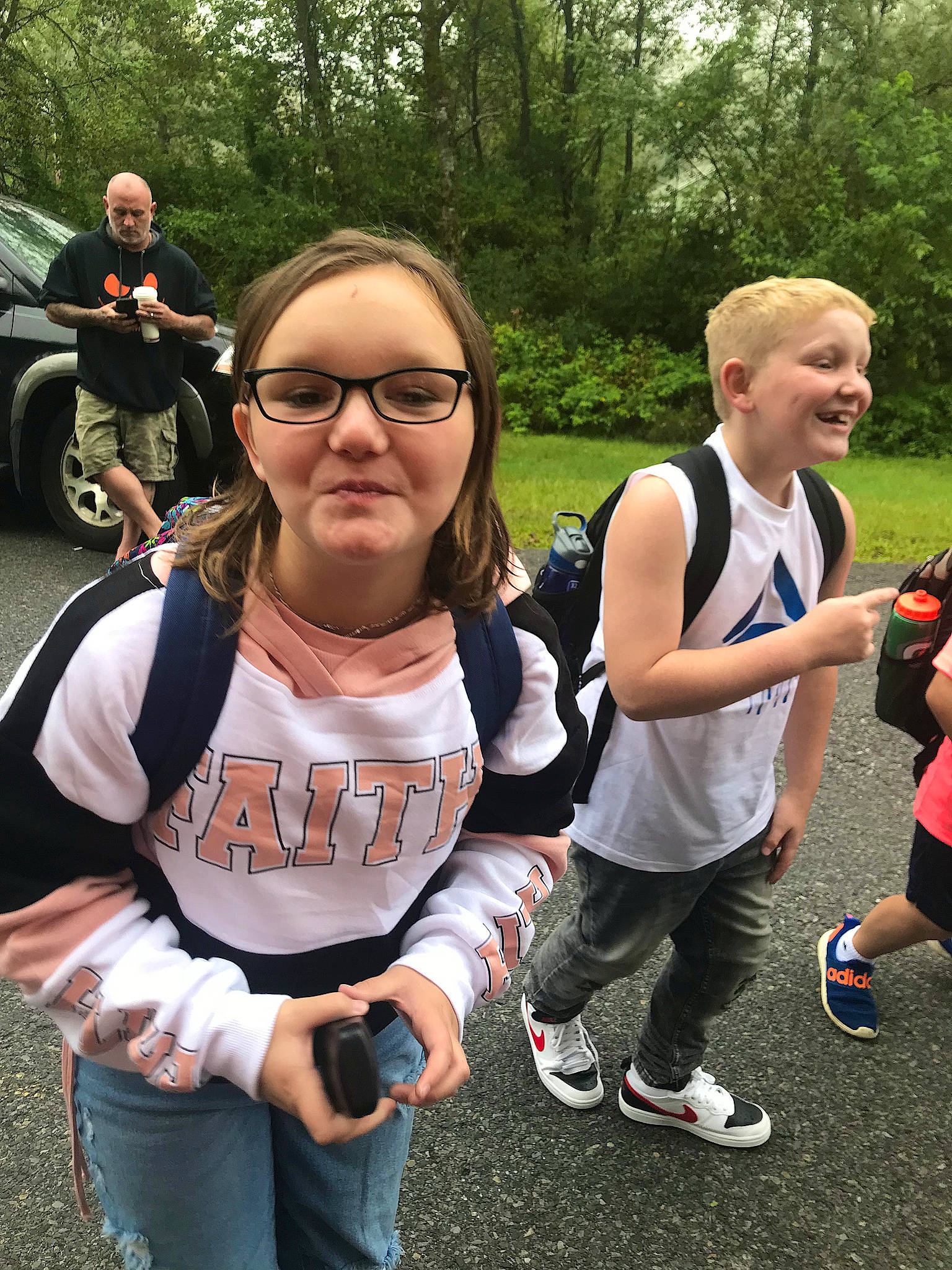 Dakota is registered to the contest to win money with this photo: crowd, eyewear, facial_expression, fun, gesture, grass, hairstyle, joy, leisure, person, plant, public_space, recreation, shorts, smile, style, summer, t_shirt, tire, tree