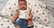 Saniyah is registered to the contest to win money with this photo: baby, infant, child, portrait, lying_down, bed, blanket, pillow, bow_headband, smiling, face, denim_skirt, sneakers, purse, bedroom, dresser, indoor, fashion, polka_dots, photography