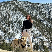 Billi joined the competition — help win amazing prizes! woman, dog, labrador, mountain, snow, trees, outdoor, nature, hiking, landscape, scenery, pet, casual_clothing, footwear, sunny, daylight, standing, leash, black_top, white_pants