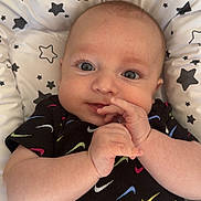 Sonny a rejoint le concours — aidez-le/la à gagner de superbes lots ! baby, infant, face, hands, smile, eyes, clothing, pattern, stars, cushion, comfort, cute, portrait, black_shirt, colorful, swoosh, lying_down, expression, young_child, indoors