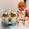 baby, infant, pumpkin_outfit, orange_hat, shaved_ice, whipped_cream, cookie, cup, table, wall, power_outlet, hand_holding_baby, food, dessert, indoor, person, cute, snack, white_background, sitting