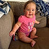 Tatum is registered to the contest to win money with this photo: baby, child, smiling, pink_onesie, couch, blanket, indoor, happy, cute, infant, person, sitting, face, skin, furniture, home, young_child, cozy, portrait, casual